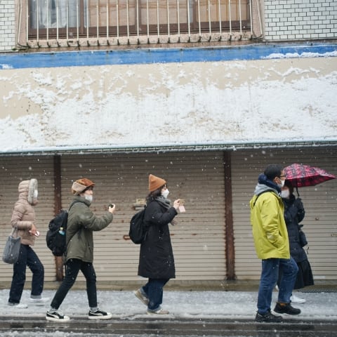 migakiba gojomeのイメージ写真。雪の五城目朝市通りを歩くmigakiba参加者を撮影した画像。スマートフォンを手に撮影をしながらフィールドワークを行っている様子が写っています。