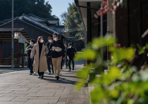 migakiba ozuのイメージ写真。フィールドワークで、古いまちなみが残る大洲城下町を現地事務局代表の井上さんと全体事務局大洲担当の神尾を先頭に、参加者とともに街歩きをしている様子が写っています。