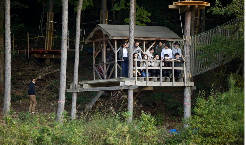 あうる京北のフィールドの「ツクル森」にあるツリーハウスに参加者15名ほどが登って、原っぱを眺めています。